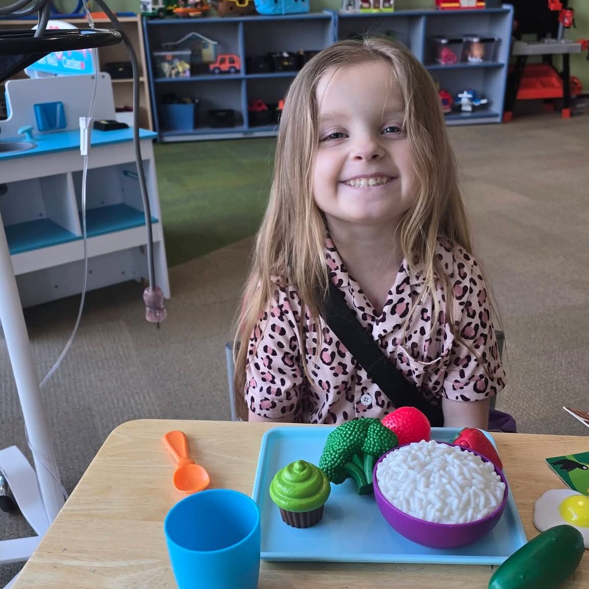 Evelyn playing with plastic food toys in her hospital room